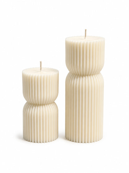 Two ribbed pillar candles in an off-white cream color, one short and one tall, standing on a white background.