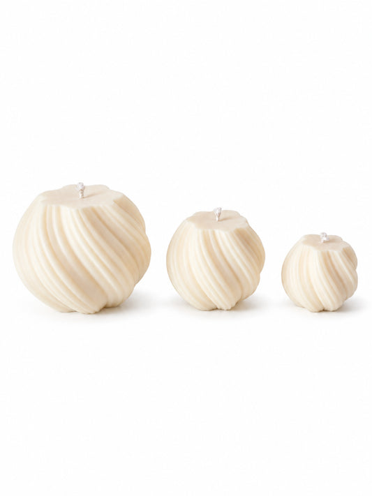Three Swirled cream-colored pillar candles in graduated sizes, arranged from left to right on a seamless white background.